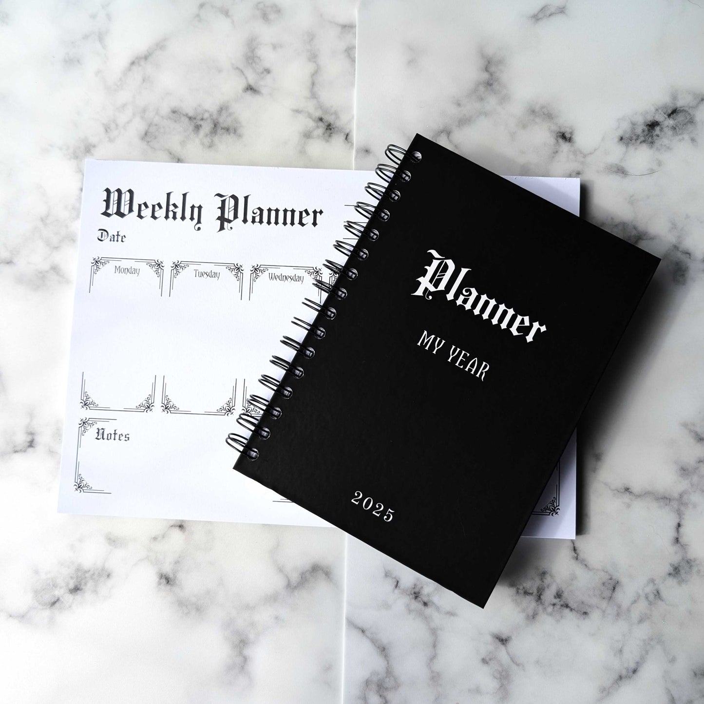 The 2025 Gothic Planner on top of the Weekly Planner Notepad by Gothic Office.