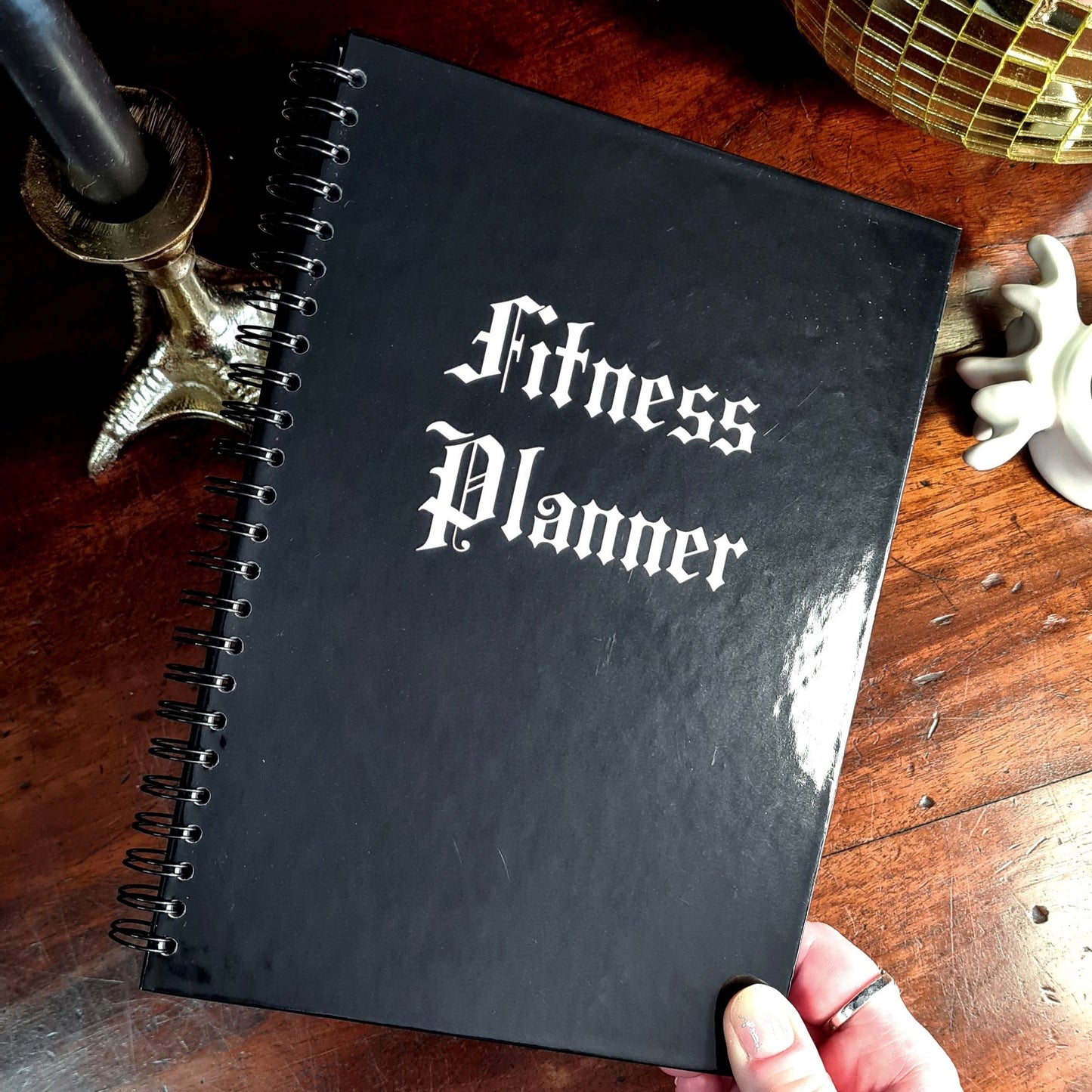A Gothic Fitness Planner with a black hardback cover that says Fitness Planner in white font.