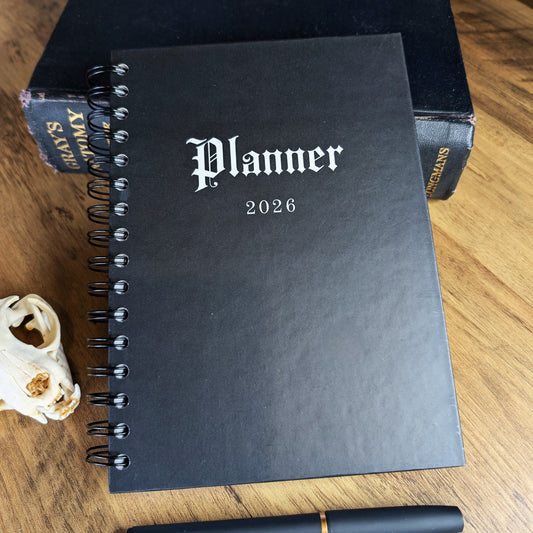 The front of the 2026 Planner by Gothic Office.  The planner is jet black with white writing saying Planner 2026 on the cover. 