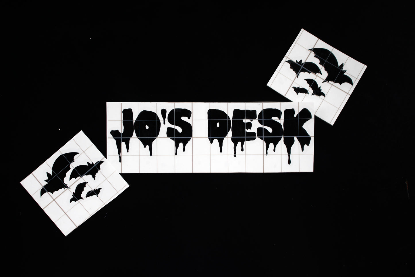 This is a personliased vinyl in a dripping font saying Jo's Desk, with bat stickers wither side. 