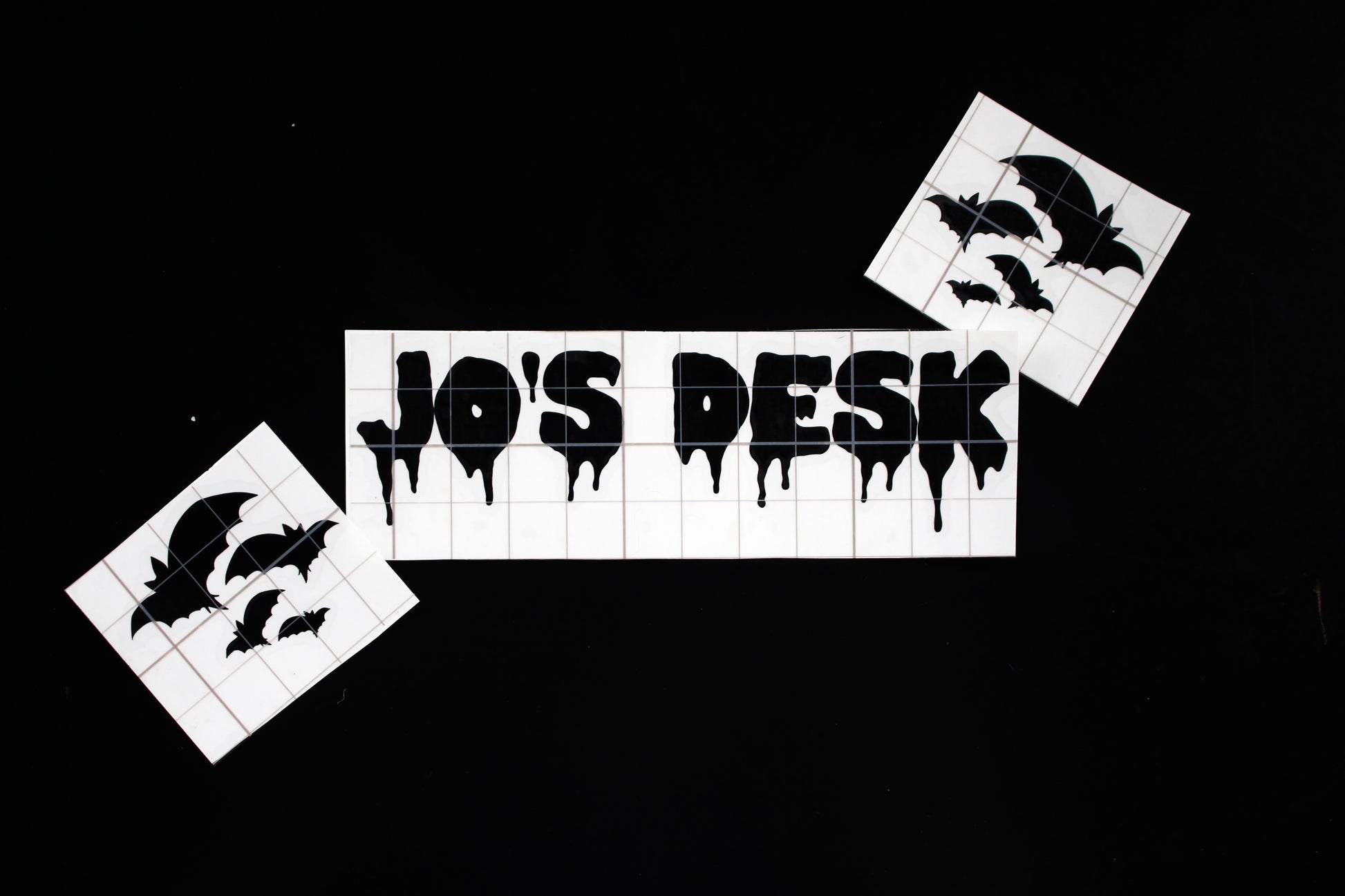 This is a personliased vinyl in a dripping font saying Jo's Desk, with bat stickers wither side. 