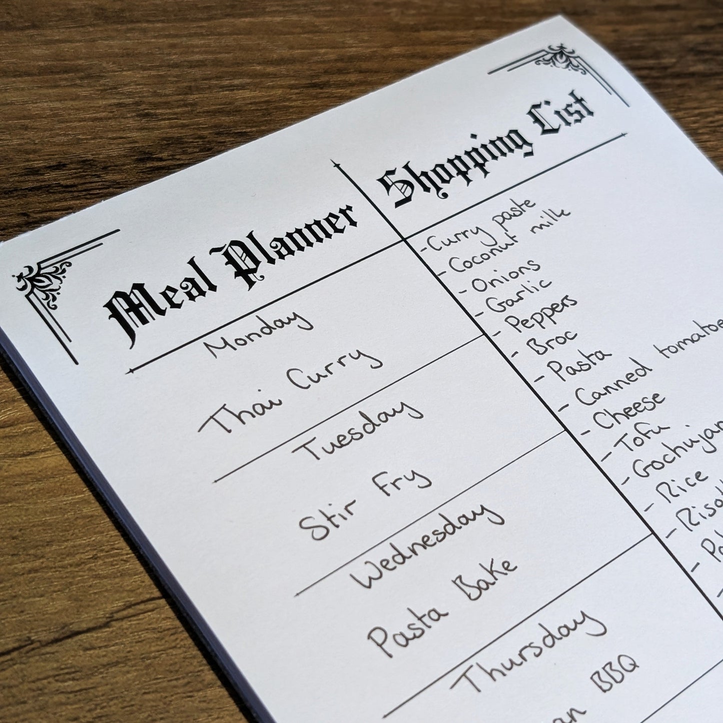 Gothic Office Meal Planner and Shopping List with meals and products hand written on it.