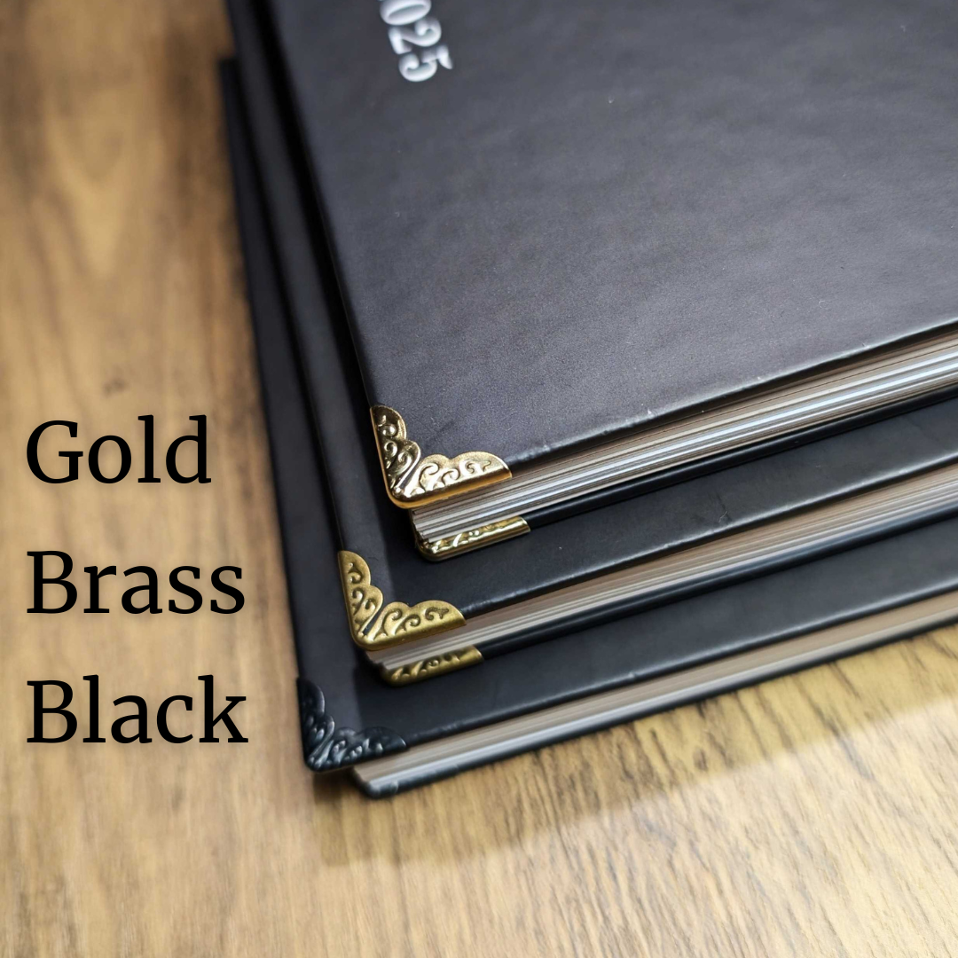 3 Planners stacked on top of each other with different metal corners, one in gold, one in brass and one in black.