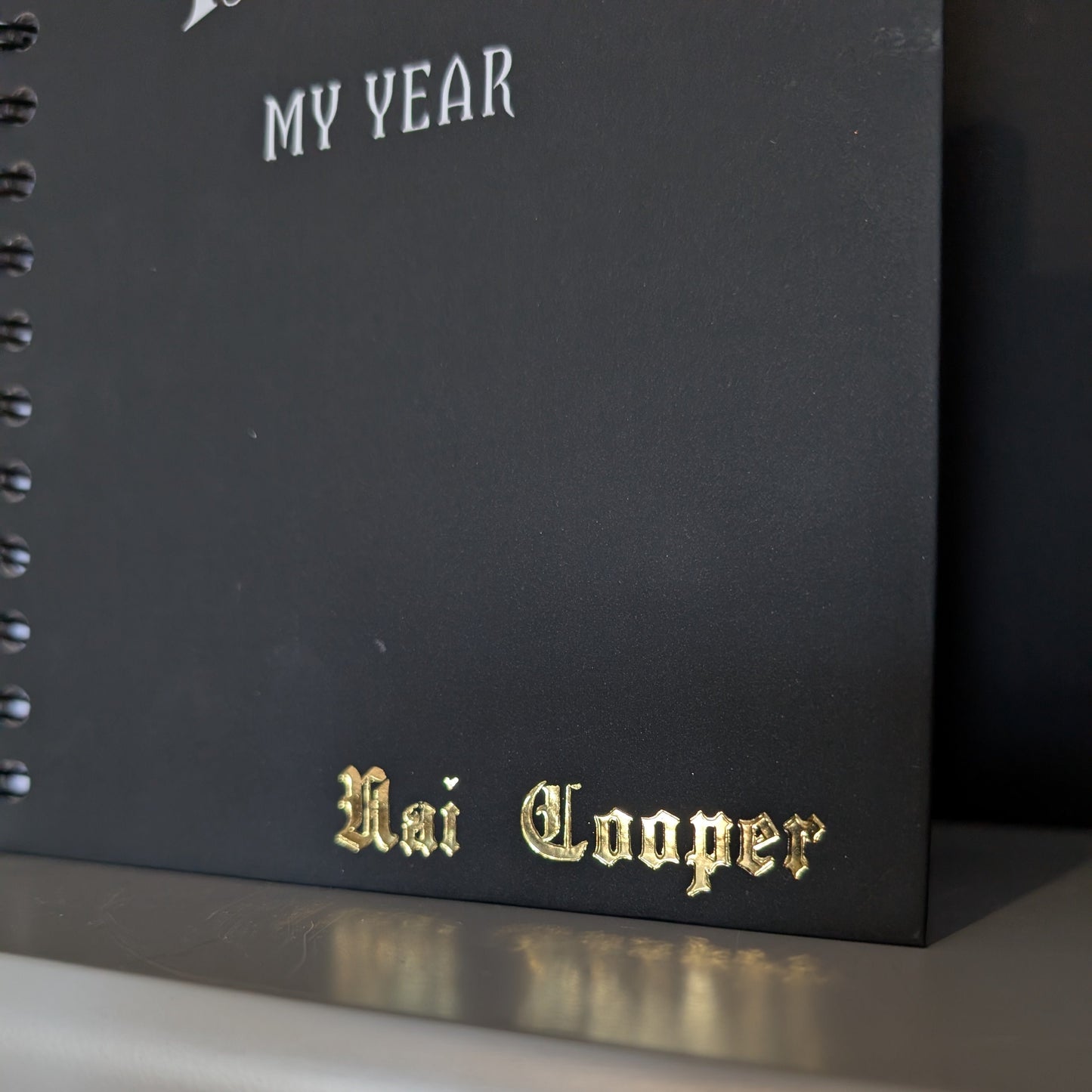 A close up of a Gothic Office planner with gold embossing of the name Nai Cooper.