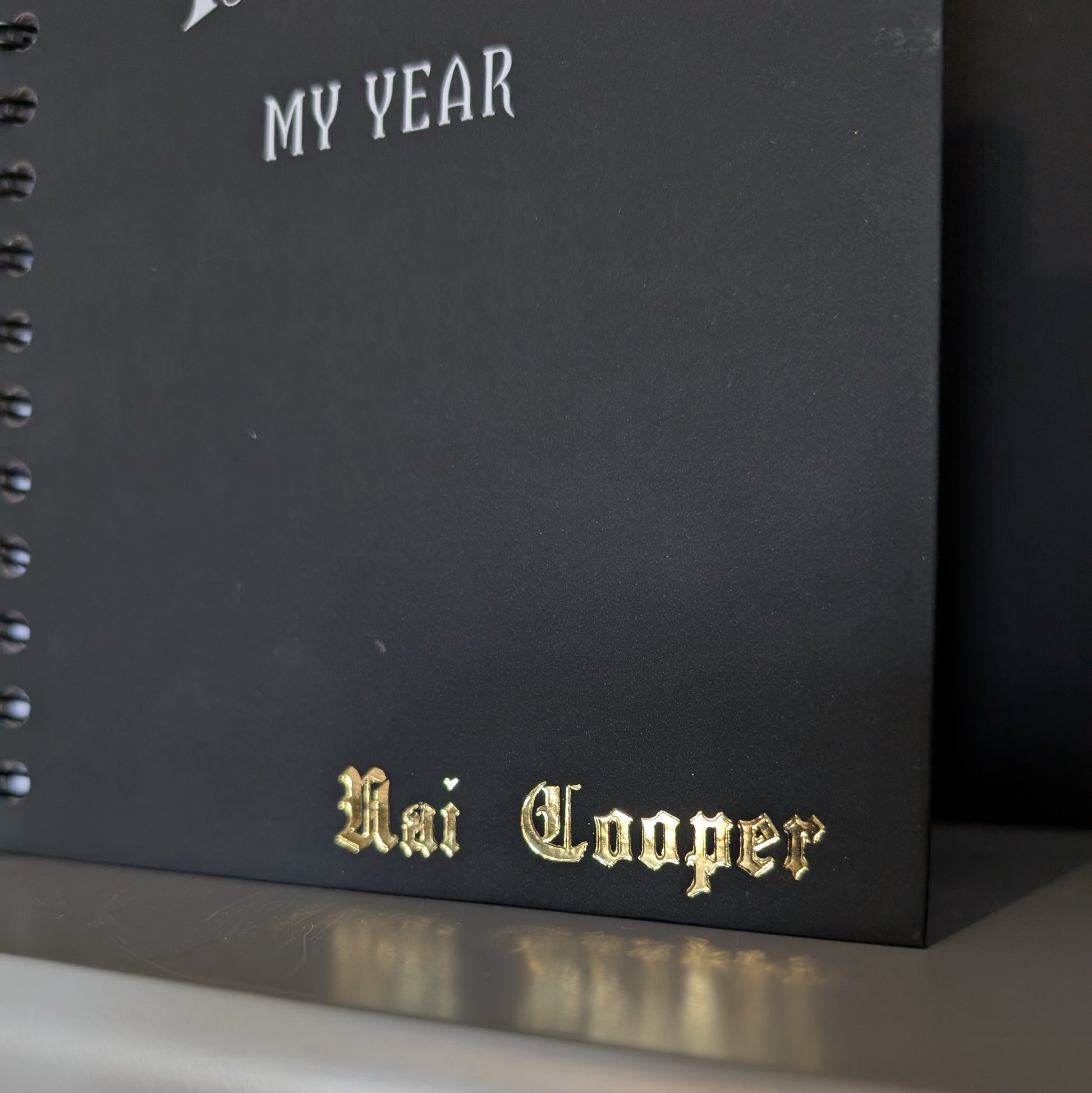 A close up of a Gothic Office planner with gold embossing of the name Nai Cooper.