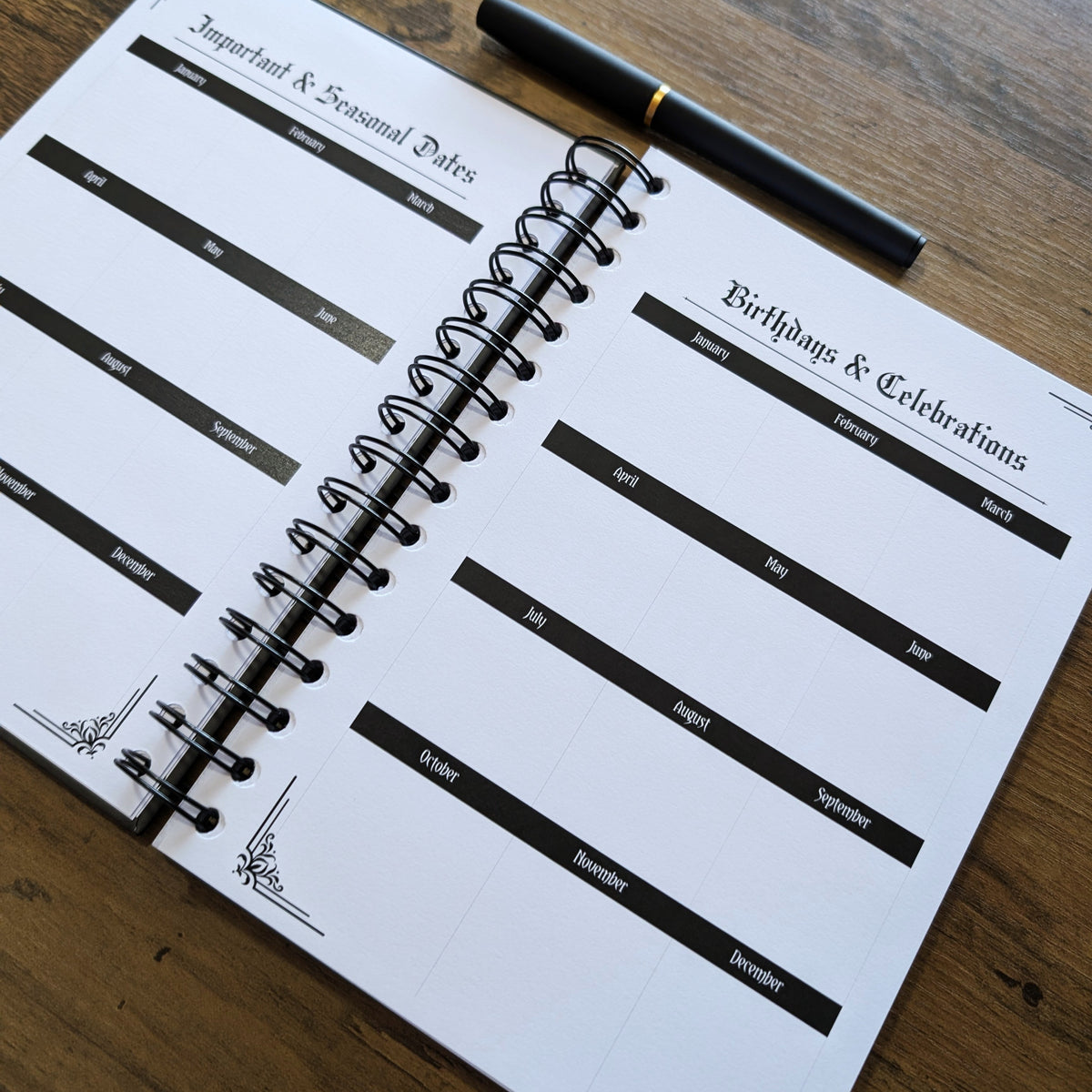An open spiral-bound planner or journal on a wooden table, showing printed sections for important seasonal dates and birthdays/celebrations, with a black pen resting on top.