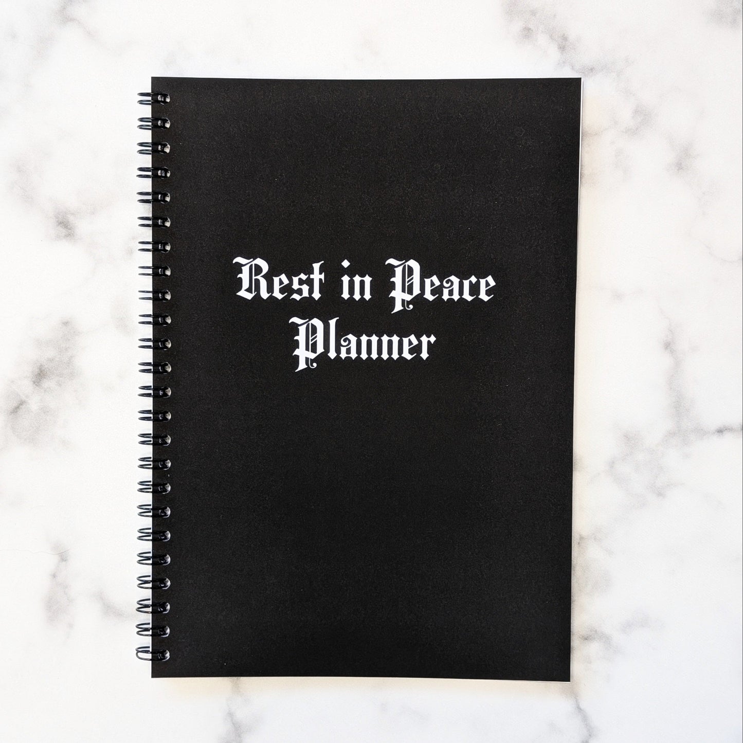 The cover of the Rest In Peace Planner by Gothic Office. It's black with white gothic font. 